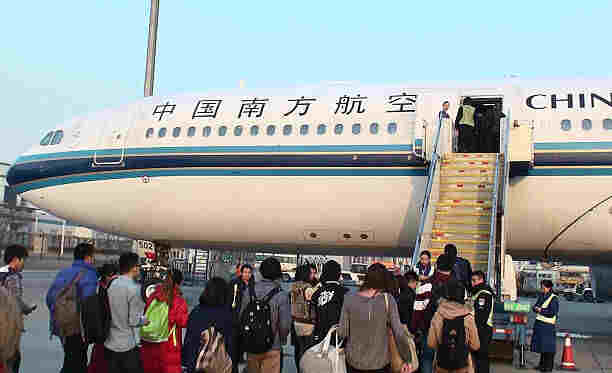 Biggest Airports in the World-Beijing, China - February 26, 2013: Looking At Four Ground Crew Two Are On Airplane Staircase And Two Are On The Ground Welcoming Passenger To Board China Southern Airlines Airplane Parked At Loading Gate Of Beijing international airport China For Departure.